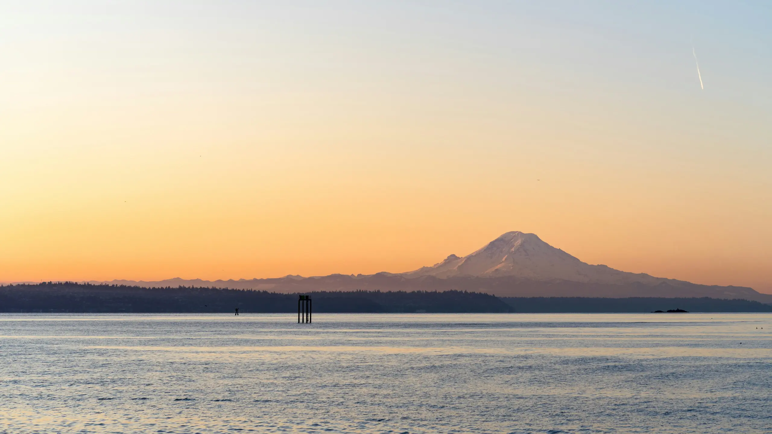 A channel marker standing in Puget Sound at sunrise, with Mount Rainier on the horizon.